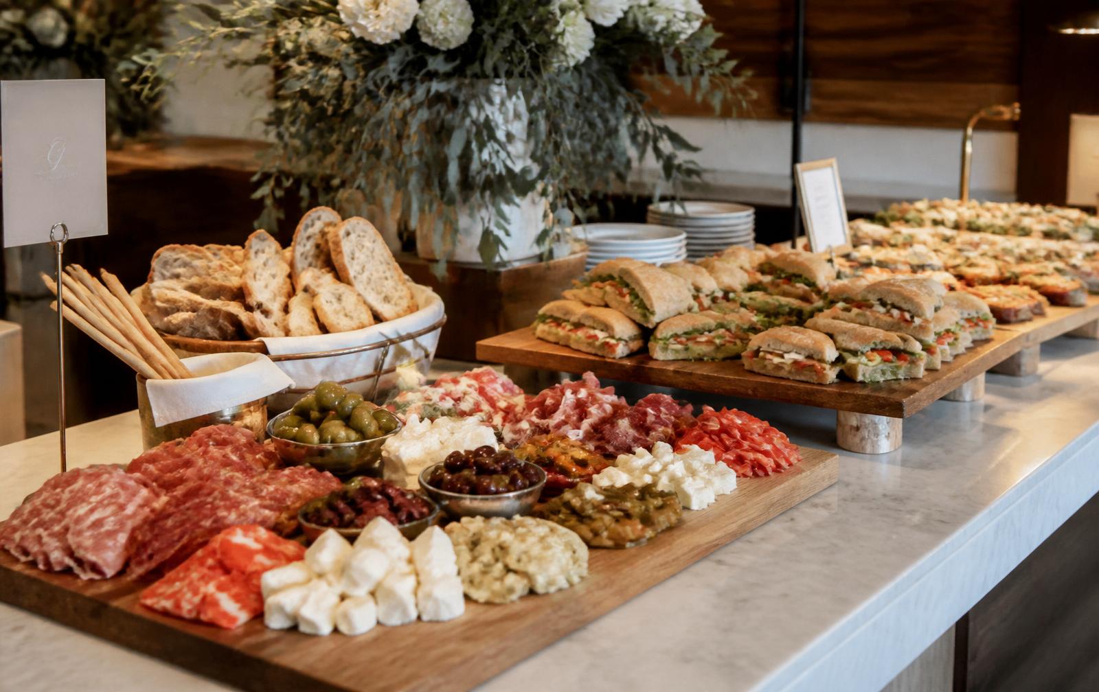 Italian catering spread with sandwiches, cured meats and antipasto